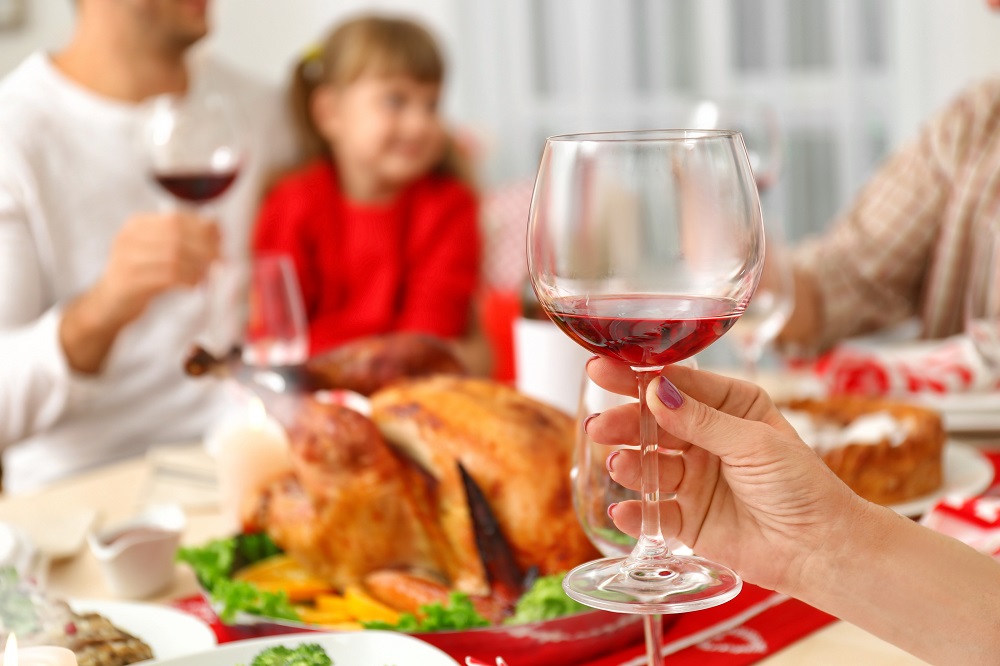 Female hand holding glass with red wine on blurred background, c