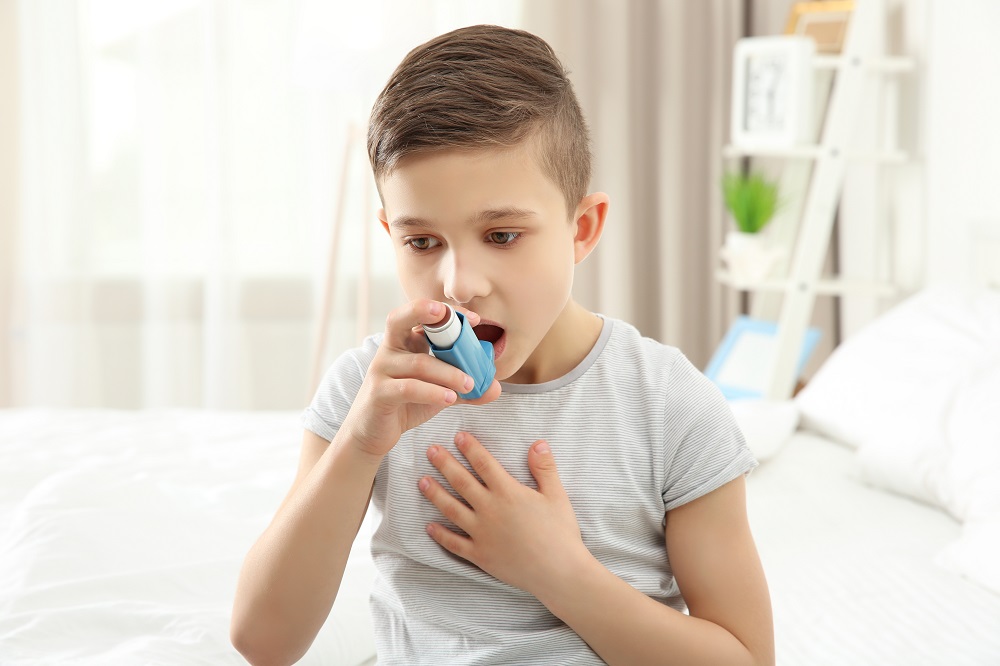 Boy using inhaler during asthmatic attack at home
