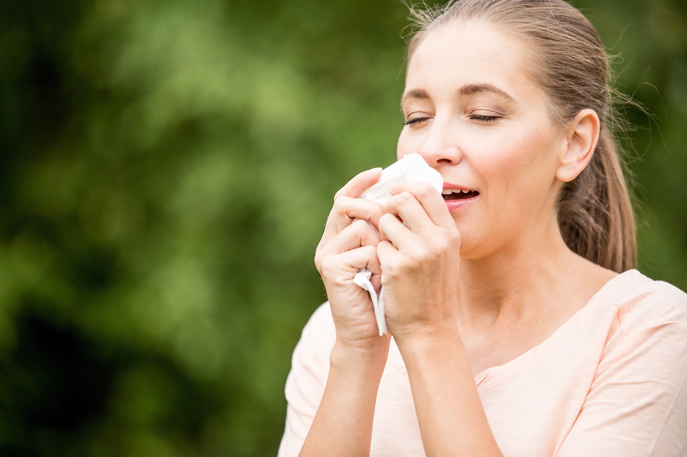 Woman with a cold sneezing from allergy or hay fever