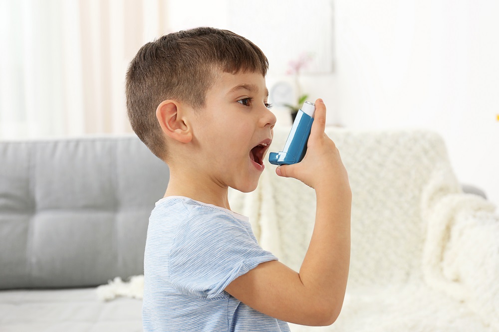 Little boy using asthma inhaler at home