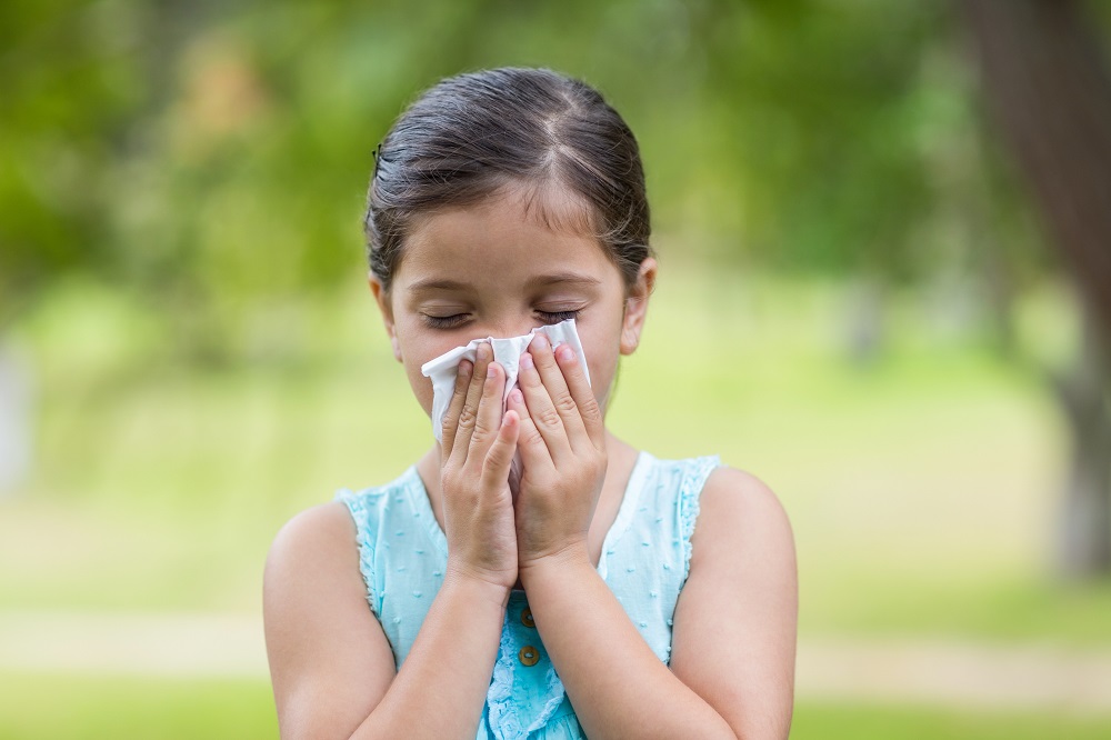 Little girl blowing his nose on a sunny day