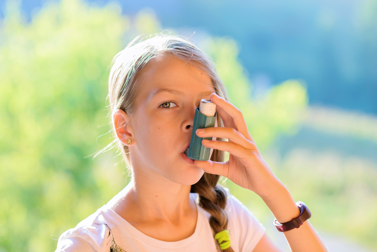 Girl using asthma inhaler in a park