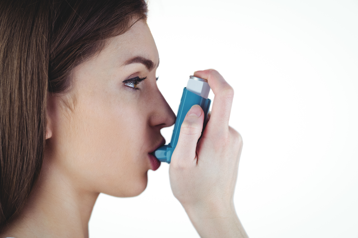 Asthmatic brunette using her inhaler