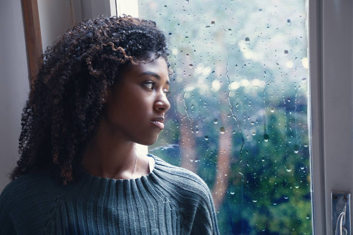 Woman looking outside in a low mood because of allergies.
