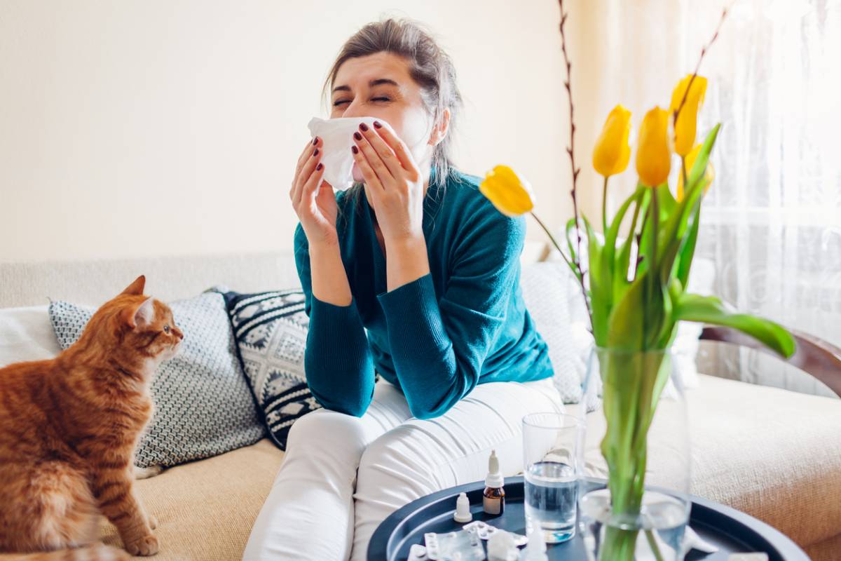 The image shows a woman sneezing due an allergic reaction. It serves to answer the question why only some people develop allergies.